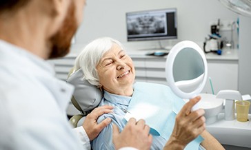 a patient checking her new dental implants with a mirror