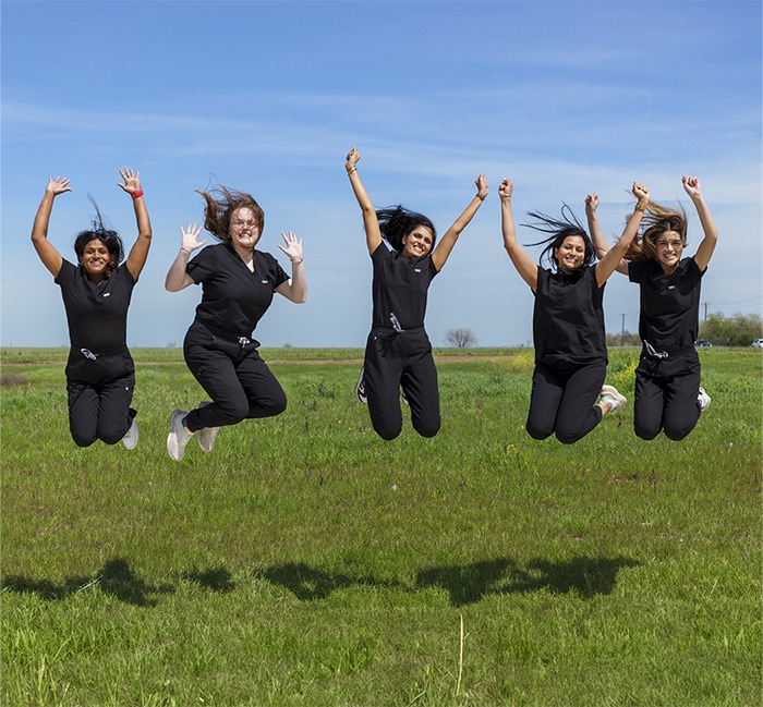 Dental team members from The Elegant Dentistry jumping in the air in the middle of a field