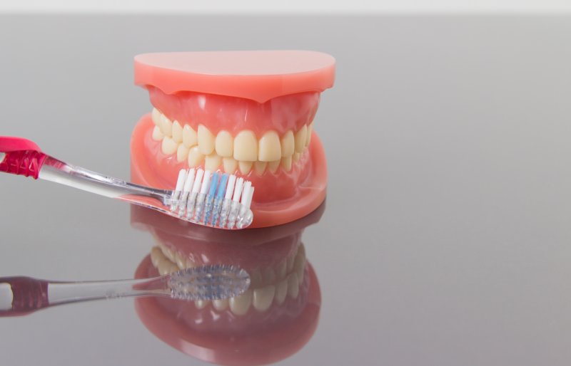 A pair of dentures sitting next to a toothbrush